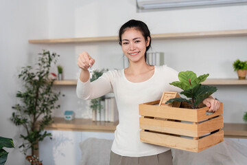 Moving and Gardening. Woman holding plant in a crate while moving into new home.