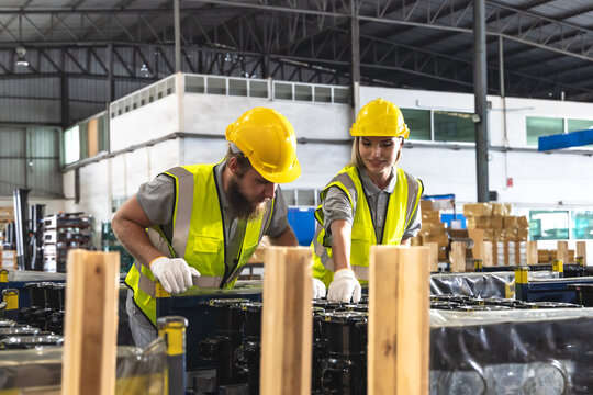 Male and female warehouse workers checking auto parts stock in distribution warehouse