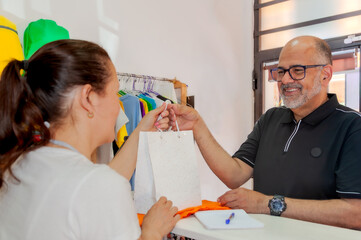 Cliente sonriente recibe con alegría una bolsa blanco con su compra