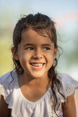 Lifestyle portrait of happy little girl smiling before the sunset in the summer