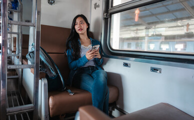 Tourist using her smartphone while traveling on a train next to the window