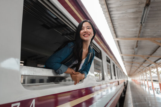 Happy tourist looking out train window while traveling by railway