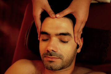 Caucasian man enjoying relaxing anti-stress head massage and pampering facial beauty skin...