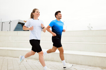 Joyful morning joggers enjoying fitness in a modern city environment under soft gray skies during...