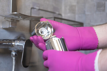Hands in bright pink gloves meticulously disassemble a shower water filter, illustrating crucial...