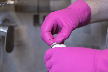 Person in pink gloves performing shower water filter replacement, emphasizing home maintenance,...
