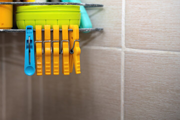 Yellow plastic clothespins hanging on a shampoo stand in a bathroom, adding a pop of color and...