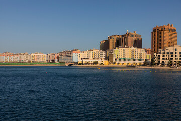 Doha, Qatar - 13 June 2025: A scenic view of vibrant residential buildings along the coast of The Pearl Island in Doha, Qatar the image shows colorful architecture, calm sea water
