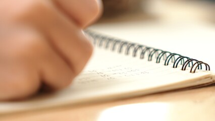 Close up of child hand taking a note or writing a letter at classroom. Happy student hands hold pen...