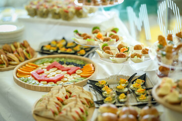 Beautifully arranged catering table with assorted finger foods, fruit platters, mini sandwiches, and desserts, perfect for weddings, receptions, and upscale events.
