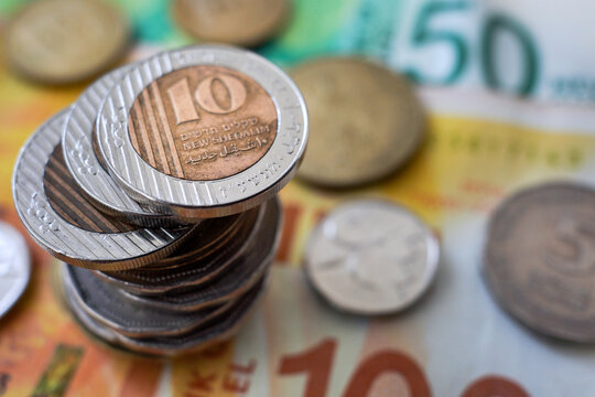 Stack of Israeli new shekel coins and banknotes, macro view.

