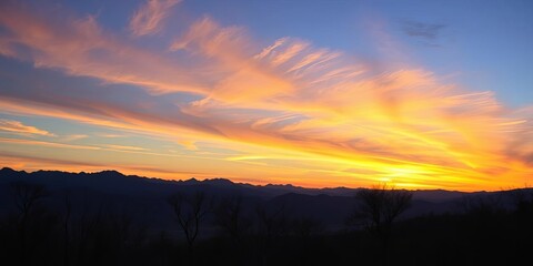 Breathtaking sunset panorama; majestic mountains, silhouetted dry trees, vibrant colors,  horizon,  view