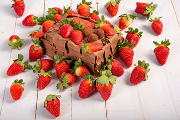 Chocolate cake with strawberries, a delicious chocolate cake covered with wonderful strawberries on rustic wood, selective focus.