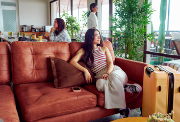 Young woman relaxing on sofa in hotel lobby, waiting for vacation to start