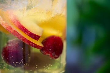Close-up of a vibrant fruit drink with ice cubes and bubbles, featuring red and yellow fruit...