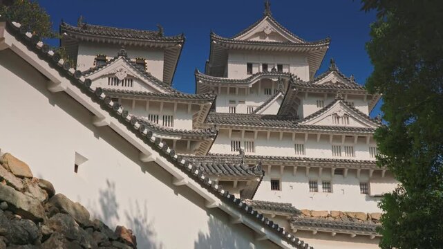 Himeji, Japan - Sep 24 2024, 4k, panoramic view of Himeji Castle, White Heron Castle from below, through tree foliage in daytime with blue sky and clouds, without people, Himeji, Japan