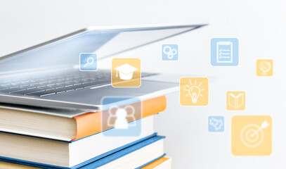 half-open laptop on a stack of books with education icons