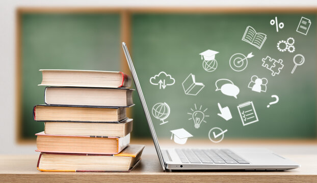 icons flying out of laptop, next to stack of books, on chalkboard background. e-learning concept