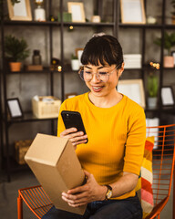 japanese woman checking box of received package or product at home