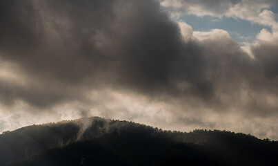 Sunset with stormy cloudy sky and bright sunrays above mountain peak. Troodos mountains Cyprus