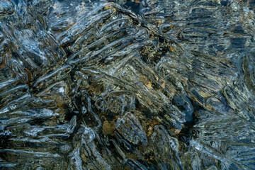 needles and crystals of melting transparent ice on the pebble shore of the northern Kolyma
