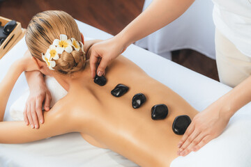 Hot stone massage at spa salon in luxury resort with day light serenity ambient, blissful woman...