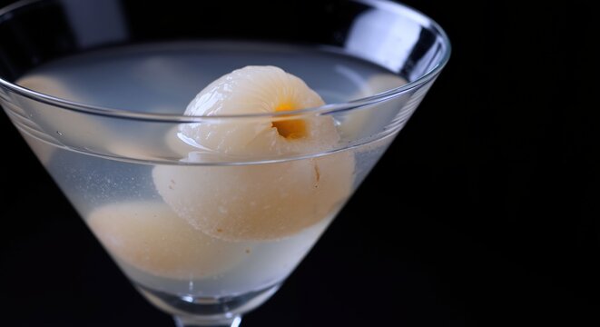 Classic martini cocktail with lychee garnish in elegant glass on dark background. Premium alcoholic drink with exotic fruit decoration for luxury bar service - Powered by Adobe