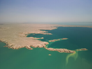Aerial view of turquoise waters winding around sandy peninsulas at Kuimazar Reservoir. Uzbekistan's...