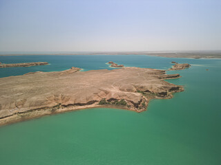 Aerial view over a wide peninsula and turquoise bays. Kuimazar Reservoir shimmers in the sun. The...