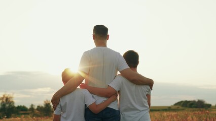Son hugs father with arms on outdoors. Kid son hugs dad on sunny meadow. Father loves his son,...
