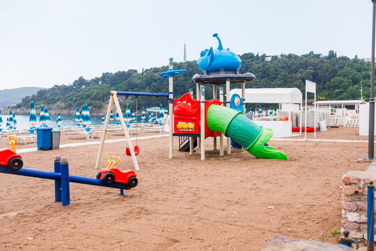 Colorful children playground on a sandy beach near the sea. Vacation concept, family tourism and beachside leisure activities for kids.