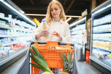 Young woman looking at product at grocery store. Costumer buying food at the market