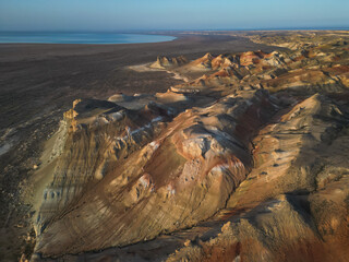 The video captures intricate sandstone hills of Aktumsuk cape, where erosion reveals layers of ochre and white. The shadows highlight each undulation, evoking ancient geological transformations