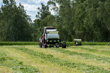 Hay Bale Wrapping Process in Countryside with White Stork in Background &ndash; Sustainable Farming Concept