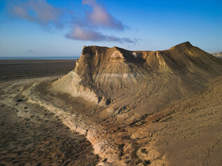 Aerial view glides above Aktumsuk's steep outcrops and harsh desert plain. Subtle color transitions accentuate the isolated and untouched environment of Uzbekistan
