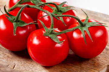 Fresh red tomatoes on a branch, on a wooden chopping board, close-up, no people,