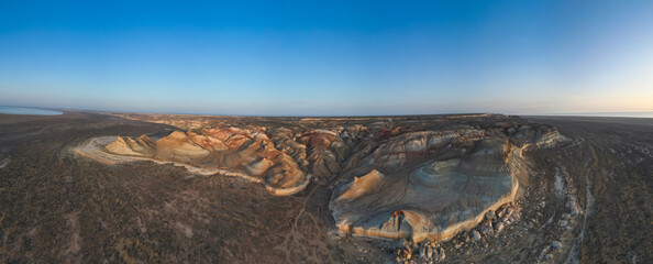 Aerial view glides along sculpted desert walls marked by centuries of erosion. The high cliffs reveal stratified history in every colored layer of stone