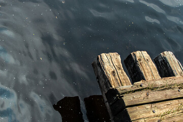 looking down at a weathered wood structure next to calm, reflective water with ripples and...