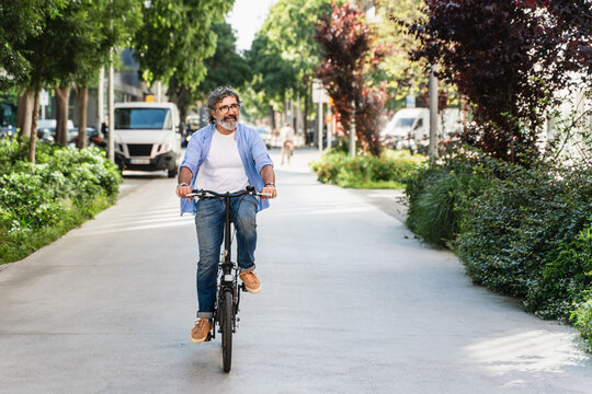 Happy mature man cycling with electric bicycle in the city enjoying sustainable mobility