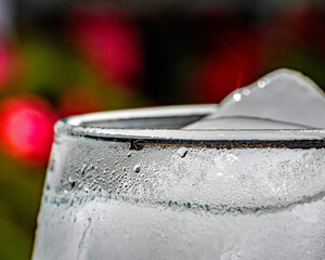 A closeup of a water glass against a red background creates an image of fire and ice 