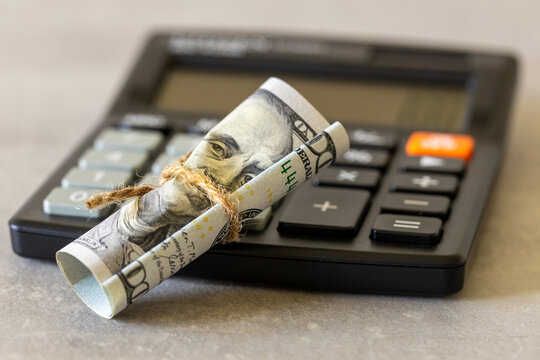 weakening dollar. Financial business concept. A 100 US dollar banknote squeezed with a string and a calculator