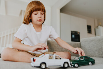 Engaged boy playing with toy cars, showcasing creativity and imagination in a cozy indoor setting...