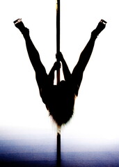 A woman in silhouette performing a pole dance.