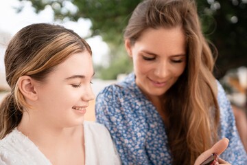Fototapeta premium Women Smartphone Outdoors Sharing Two women share smartphone outdoors, daytime casual connection, sharing information or photos.