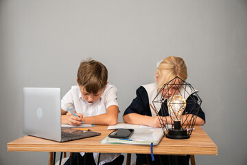 Children Studying Homework Table Laptop - Two children sit at a table, focused on their homework,...