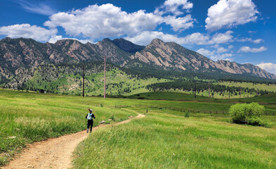 Jogger on Boulder, Colorado's Doudy Draw Trail with the Flatirons in the background