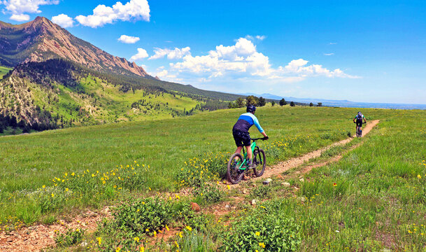 Mountain bikers on Boulder, Colorado's Springbrook Trail with the Flatirons in the background