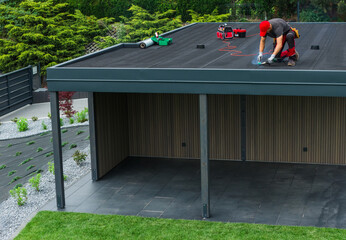 Construction Worker Installing Roofing on a Residential Structure in a Landscaped Yard