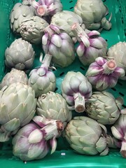 Fototapeta premium Fresh artichokes displayed in green container for healthy cooking and grocery shopping