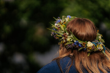 Close-up of a flower crown made of colorful wildflowers and greenery on a woman's brown hair,...